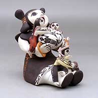 A sitting grandmother storyteller figure with three children, a pot and a turtle, click or tap to see a larger version