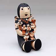 A sitting grandmother storyteller figure with nine tiny children on her
 by Dena Suina of Cochiti