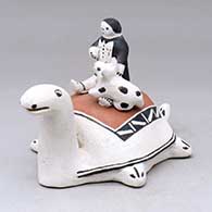 A polychrome turtle figure with a child and puppy on its shell
 by Toni Suina of Cochiti