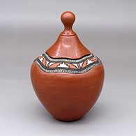 A lidded red jar with a lightly carved band around the neck decorated with a painted geometric design
 by Betty Jean Fragua of Jemez