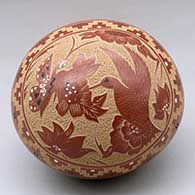 A polychrome seed pot decorated with a sgraffito and painted hummingbird, butterfly, flower and geometric design
 by Helen Tafoya of Jemez