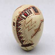 A miniature polychrome seed pot decorated with a lightly carved, sgraffito and painted yeibichai, arrow, rainbow and geometric design, with one inlaid stone
 by Glendora Fragua of Jemez