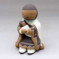 A grandmother storyteller holding one child and sitting on a rock
 by Stella Teller of Isleta