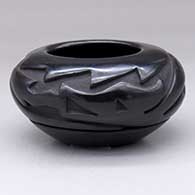 An oval black bowl carved with an avanyu design around the shoulder
 by Denise Chavarria of Santa Clara