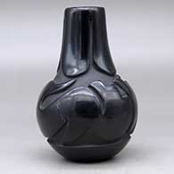 A black wedding vase decorated with a ring of feathers carved around the neck and an avanyu design carved around the shoulder, click or tap to see a larger version