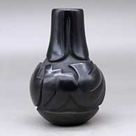 A black wedding vase decorated with a ring of feathers carved around the neck and an avanyu design carved around the shoulder, click or tap to see a larger version