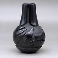 A black wedding vase decorated with a ring of feathers carved around the neck and an avanyu design carved around the shoulder, click or tap to see a larger version