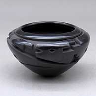 A black bowl carved around the body with a stylized avanyu, kiva step and geometric design
 by Effie Garcia of Santa Clara