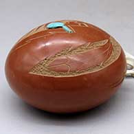A small red spoutless canteen decorated on top with a sgraffito pueblo dancer, feather and geometric design, click or tap to see a larger version