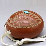 A small red spoutless canteen decorated on top with a sgraffito pueblo dancer, feather and geometric design, click or tap to see a larger version