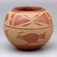 A red bowl decorated with a four panel sgraffito roadrunner, butterfly and geometric design
 by Corn Moquino of Santa Clara