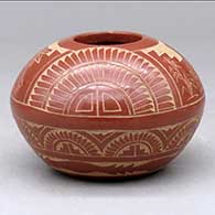 A red seed pot decorated with a sgraffito pueblo dancer, feather, corn stalk and geometric design
 by Tom Tapia and Sue Tapia of Ohkay Owingeh and Laguna