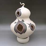 A large polychrome bulbous jar with a lid and geometric cutouts in a lightly carved, sgraffito and painted tiny square, flower and geometric design, with a custom matching stand
 by Diego Valles of Mata Ortiz and Casas Grandes