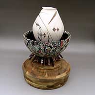 A two-piece set with a polychrome jar with an organic cut opening and flowing geometric design sitting in a stamped, carved and painted bowl symbolizing ancient earth with a forest of crystals hanging off the bottom above a custom wood stand
 by Diego Valles of Mata Ortiz and Casas Grandes