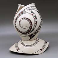 A polychrome jar with a cut geometric opening and decorated with a two-panel Paquime-style flowing geometric design with a matching custom stand, click or tap to see a larger version