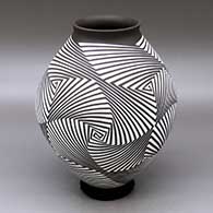 A white on dark brown jar with a flared rim and decorated with a four panel spiraling geometric design
 by Rodrigo Perez of Mata Ortiz and Casas Grandes