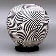 A black on beige jar decorated with a four panel spiraling geometric design, click or tap to see a larger version