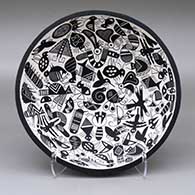 An open black-on-white bowl decorated inside with multiple Mimbres animal and insect forms and with a band of geometric design around the exterior
 by John F Aragon of Acoma