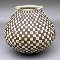 A black-on-tan jar with a flared rim and decorated with a checkerboard and dot geometric design
 by Juan Quezada Sr of Mata Ortiz and Casas Grandes