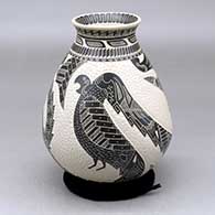 A black on white jar with a flared rim and decorated with a lightly carved and sgraffito two panel parrot and geometric design
 by Eduardo Quintana of Mata Ortiz and Casas Grandes