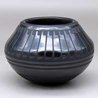 A black on black bowl decorated with a ring of feathers above the shoulder and a geometric design below
 by Blue Corn of San Ildefonso