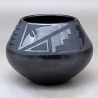 A black on black bowl decorated above the shoulder with a four-panel bat wing, kiva step and geometric design
 by Maria Martinez of San Ildefonso