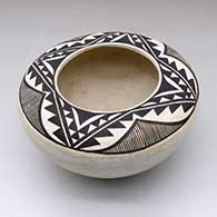 A black-on-white flat-topped jar decorated above the shoulder with a four-panel geometric design
 by Stella Shutiva of Acoma