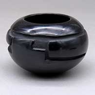 A small black bowl carved with a stylized avanyu design around the shoulder
 by Joy Cain of Santa Clara