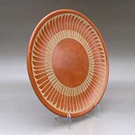 A buff on red plate decorated with a ring of feathers geometric design, click or tap to see a larger version