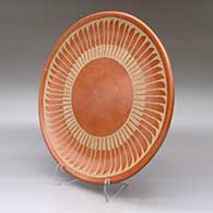 A buff on red plate decorated with a ring of feathers geometric design, click or tap to see a larger version
