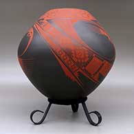 A red on brown jar decorated with a three-panel bird element and geometric design, click or tap to see a larger version