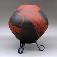 A red on brown jar decorated with a three-panel bird element and geometric design, click or tap to see a larger version