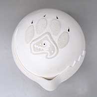 A white seed pot decorated with an applique ribbon and bear paw with cutouts for the claws
 by Wilfred Garcia of Acoma