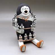 A sitting grandmother storyteller holding twelve small children
 by Martha Arquero of Cochiti