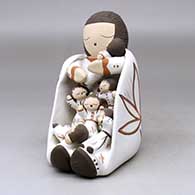 A sitting grandmother storyteller figure with a long twist of hair and wearing a manta with six children
 by Chris Teller of Isleta