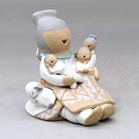 A sitting grandmother storyteller figure wearing a skirt and holding three children plus a lamb
 by Stella Teller of Isleta