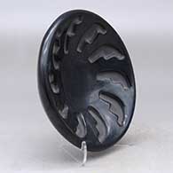 A shallow black bowl carved with a ring of feathers design, click or tap to see a larger version