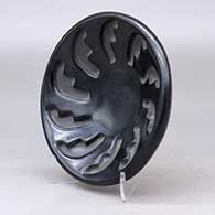 A shallow black bowl carved with a ring of feathers design, click or tap to see a larger version