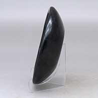 A shallow black bowl carved with a ring of feathers design, click or tap to see a larger version