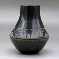 A black on black jar decorated with an avanyu, cloud, spider and geometric design, plus an inlaid stone, click or tap to see a larger version