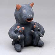 A red and black singing bear holding two cubs
 by Unknown of Cochiti