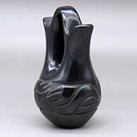 A small black wedding vase decorated with a carved stylized avanyu around the body, click or tap to see a larger version