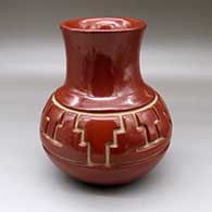 A red water jar with a tall recurved neck and carved around the shoulder with a four panel kiva step and geometric design
 by Jennie Trammel of Santa Clara
