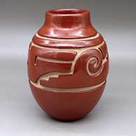 A red water jar with a short neck and carved around the shoulder with a stylized avanyu design
 by Jennie Trammel of Santa Clara