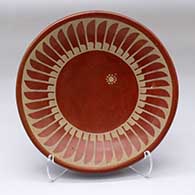 A tan on red plate decorated with a ring of feathers and geometric design
 by Santana Martinez of San Ildefonso