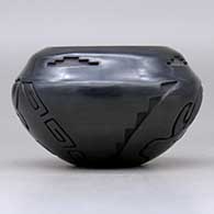 A black jar with a notched rim and carved with an elk and a bighorn  ram design around the body, click or tap to see a larger version