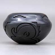 A black jar with a notched rim and carved with an elk and a bighorn  ram design around the body, click or tap to see a larger version
