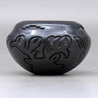 A black jar with a notched rim and carved with an elk and a bighorn  ram design around the body, click or tap to see a larger version