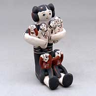 A polychrome young maiden sitting and holding six children
 by Inez Ortiz of Cochiti
