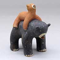 A small black bear figure with a cub sprawled across its back
 by Louis Naranjo of Cochiti